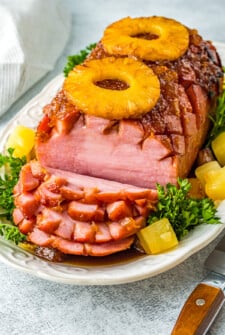 A boneless air-fryer baked ham with several serving slices cut.