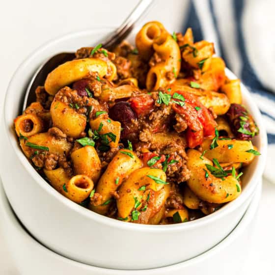 A white bowl is filled with cheesy goulash.