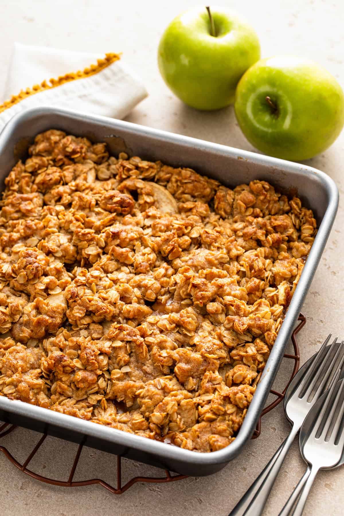 Old‑fashioned Apple Crisp is made with tender, juicy apples baked under a cinnamon‑oat crumble topping. Serve it warm with ice cream! A baked apple crisp in a square metal pan sits on a cooling rack, with a golden oat topping.
