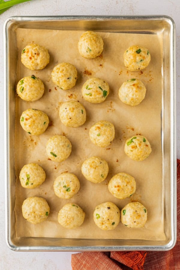 These sweet and savory Asian Chicken Meatballs are infused with fresh ginger and garlic, then baked and coated in a sticky honey-soy glaze. Baked chicken meatballs on a baking sheet.