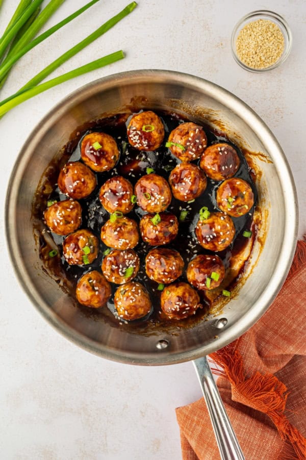 These sweet and savory Asian Chicken Meatballs are infused with fresh ginger and garlic, then baked and coated in a sticky honey-soy glaze. Cooked meatballs tossed in a saucepan with asian sauce.