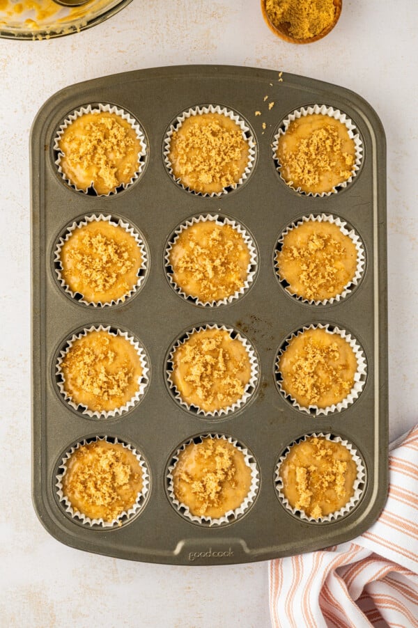 Made in one-bowl in just 25 minutes, these easy Brown Sugar Banana Muffins are extra moist with a caramelized brown sugar crunchy topping! Paper liners in a muffin tin filled with batter and topped with brown sugar.