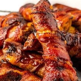 Close-up of a stack of grilled BBQ bacon-wrapped shotgun shells recipe, glazed and crispy.