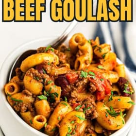 Goulash served in a white bowl with vibrant herbs on top.