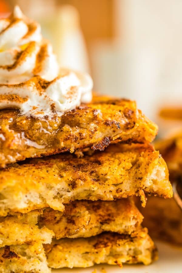 Packed with pumpkin pie flavor, this quick and easy pumpkin French toast, served with maple syrup or powdered sugar, will disappear quickly! A stack of pumpkin spice French toast topped with whipped cream.