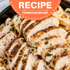 Sliced chicken breast on top of fettuccine in alfredo sauce.