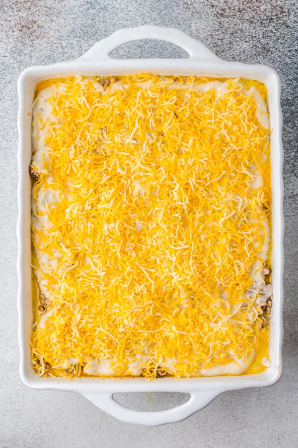 This easy Sausage Biscuits and Gravy Casserole recipe is filled with hearty layers of flaky biscuits, cheesy eggs, and creamy sausage gravy! Shredded cheddar cheese added over a layer of gravy.