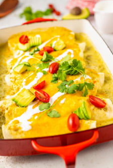 Breakfast enchiladas with crema, cilantro, avocado, and tomatoes.