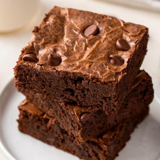 A stack of rich brownies from scratch are placed on a white plate.