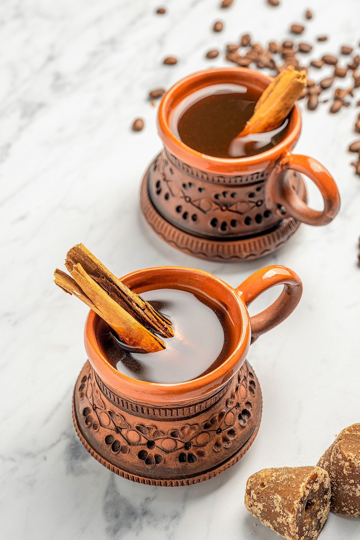 Full of warm spices and piloncillo, this comforting Café de Olla is an authentic Mexican Coffee recipe to warm you up on a cold morning. Two clay mugs full of Café de Olla with cinnamon sticks.