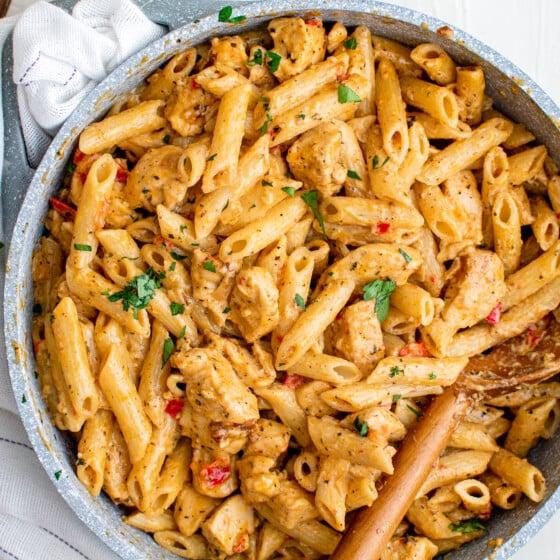 A pot of creamy pasta with chicken and peppers.