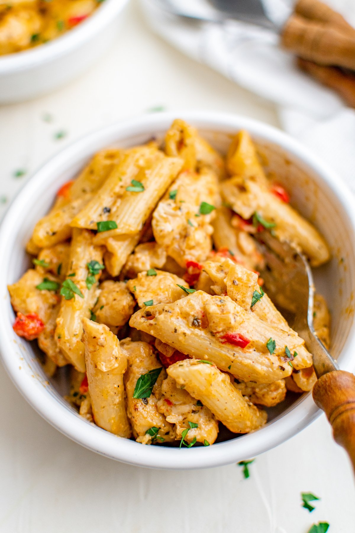 This flavorful and creamy Cajun Chicken Pasta recipe is one of our favorite restaurant style dishes to make at home in just 30 minutes! A bowl of creamy Cajun Chicken Pasta with fresh herbs on top and fork ready to take a bite.