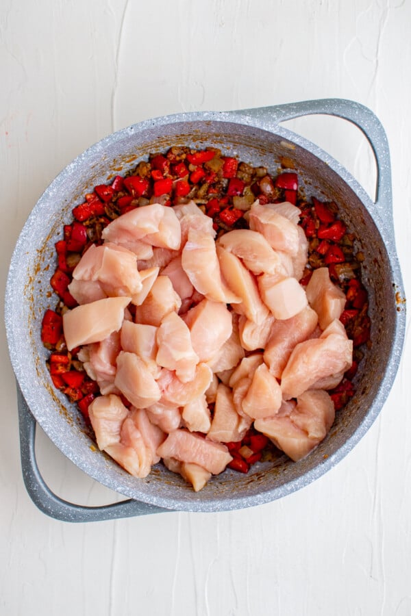 This flavorful and creamy Cajun Chicken Pasta recipe is one of our favorite restaurant style dishes to make at home in just 30 minutes! Chicken in a pan with red bell pepper.