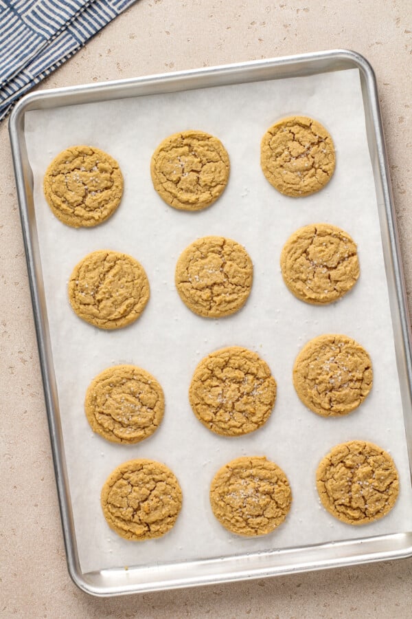The BEST chewy peanut butter cookies with soft chewy centers, crispy edges and tons of peanut butter flavor! Easy recipe ready in 30 minutes! Peanut butter cookies on a cookie sheet lined with parchment paper.