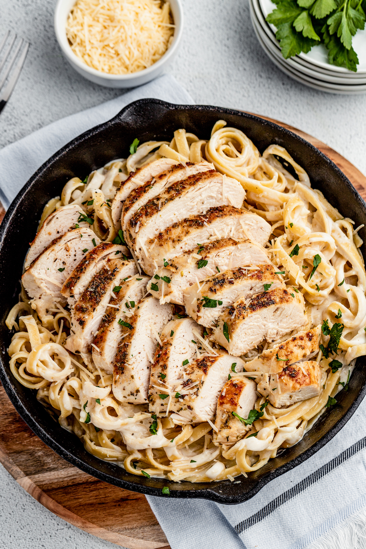 Chicken Alfredo is an easy weeknight dinner that’s worthy of a special occasion, with juicy chicken and a garlicky Parmesan cream sauce. Overhead shot of a cast-iron skillet with pasta and chicken.