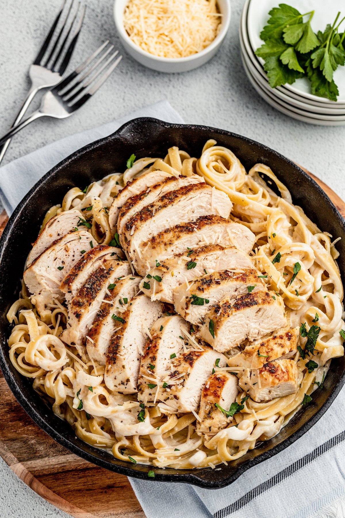 Chicken Alfredo is an easy weeknight dinner that’s worthy of a special occasion, with juicy chicken and a garlicky Parmesan cream sauce. A skillet of creamy pasta, topped with sliced sauteed chicken.