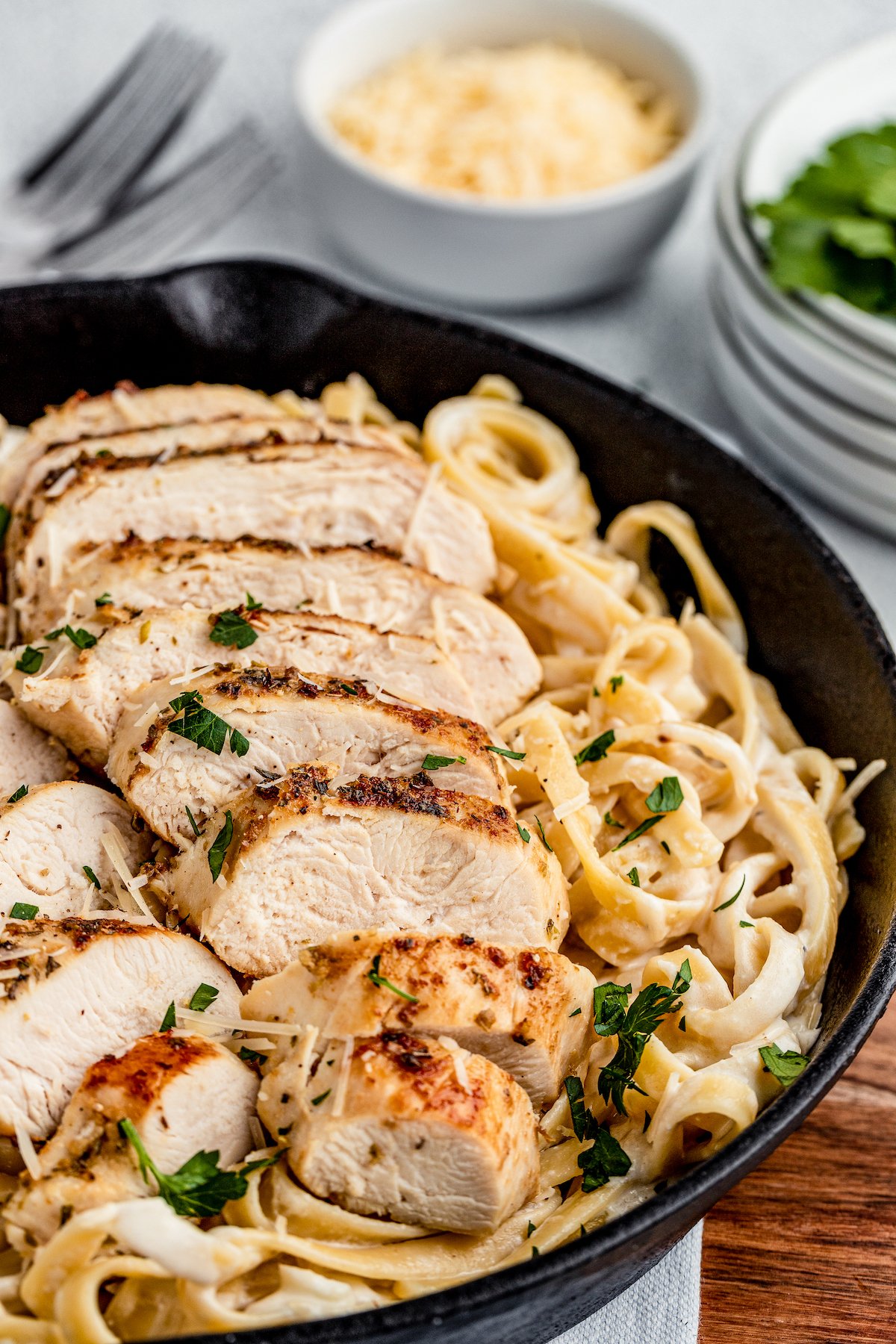 Chicken Alfredo is an easy weeknight dinner that’s worthy of a special occasion, with juicy chicken and a garlicky Parmesan cream sauce. Chicken fettuccine alfredo, garnished with parsley, in a cast-iron skillet.