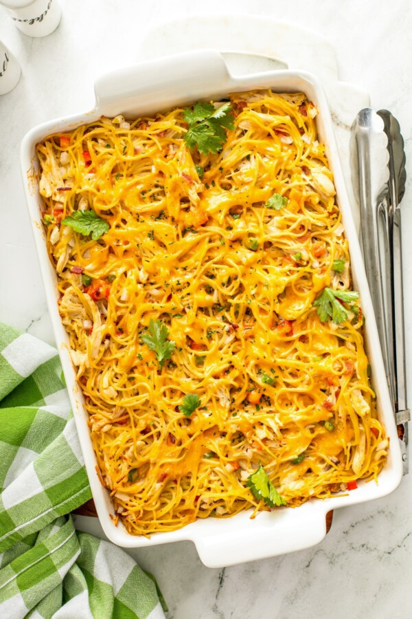 This Chicken Spaghetti recipe is quick, easy, and loaded with flavor. The secret? It's loaded with bacon and a delicious creamy cheese sauce! Fresh herbs garnish a cheesy chicken, bacon and pasta casserole.