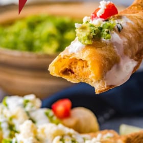 A bite taken out of a chicken taquito.