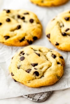 Thick chocolate chip cookies with crisp edges and soft, chewy centers arranged on a cooling rack.