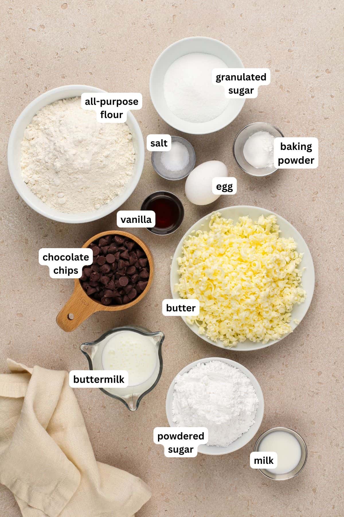 Made with simple ingredients, these Chocolate Chip Scones are perfectly flaky, soft, and buttery, with lots of melty chocolate chips! The ingredients for chocolate chip scone recipe in order from top to bottom: all purpose flour, granulated sugar, salt, egg, baking powder, vanilla, chocolate chips, butter, buttermilk, powdered sugar, milk.