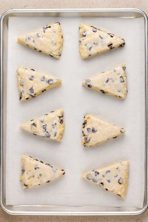 Made with simple ingredients, these Chocolate Chip Scones are perfectly flaky, soft, and buttery, with lots of melty chocolate chips! Uncooked chocolate chip scones are spread on a prepared baking sheet.