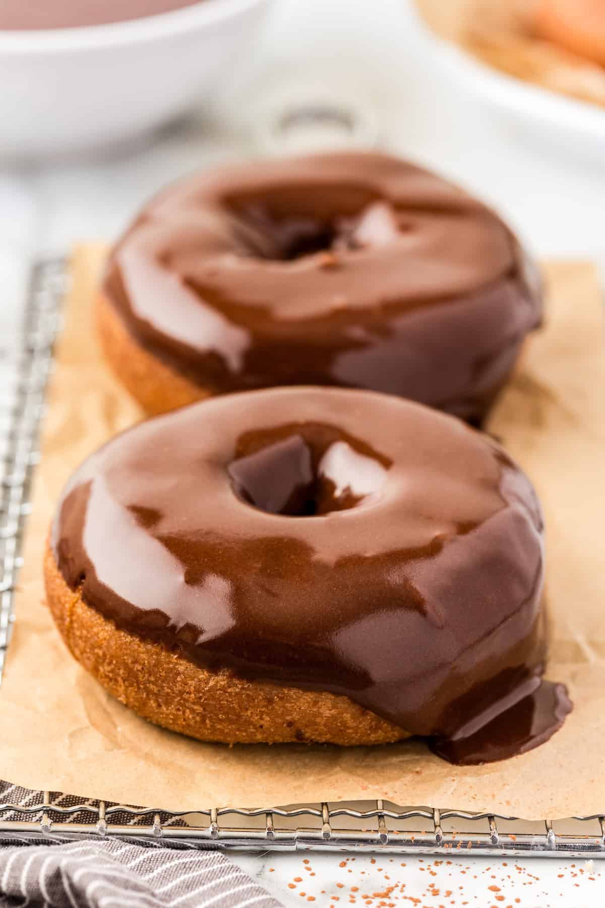 Perfectly rich and smooth, this easy Chocolate Glaze recipe is made with only 4 ingredients: powdered sugar, cocoa powder, milk and vanilla. Two donuts are topped with chocolate glaze.