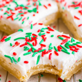 Up close image of a sugar cookie bar with white icing and a bite taken out of it on a cookie cooling rack.