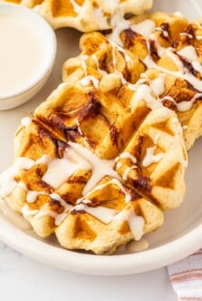 Cinnamon rolls cooked in a waffle maker and drizzled with cream cheese syrup.