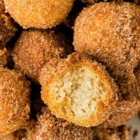 A donut hole coated in cinnamon sugar has been bitten into.