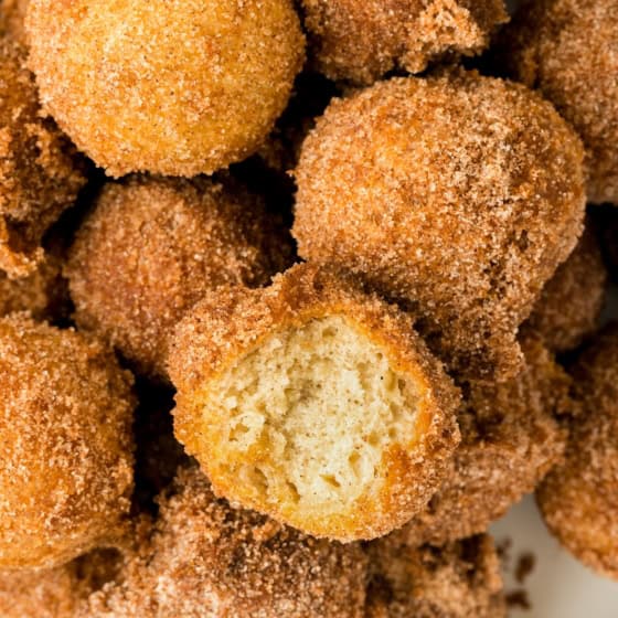 A single donut hole has been bitten into and placed back in the pile.