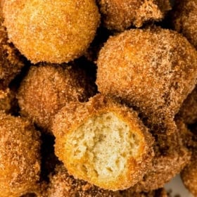 A batch of freshly made cinnamon sugar donut holes are presented in a small pile.