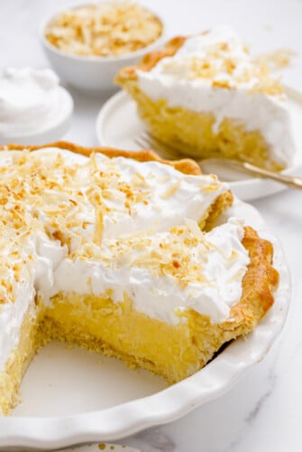 Coconut cream pie in a pie dish with the pie cut into slices.