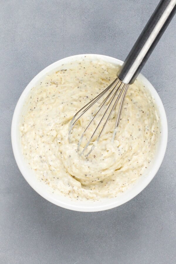 This creamy Garlic Parmesan Chicken recipe is a low-carb dinner that is packed with flavor, but made easy with just 4 simple ingredients! Mayonnaise, cheese and seasonings are being whisked in a bowl.