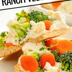Close-up of sliced ranch crescent roll veggie pizza on a plate, topped with broccoli, cauliflower, and carrot slices.