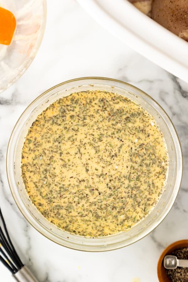 Skip the canned soup! This easy Crockpot Chicken and Gravy recipe is made from scratch - just real ingredients, creamy gravy, and big flavor! A glass bowl filled with a mixture of seasonings, dry milk powder, water and chicken bouillon sits on a marble countertop.