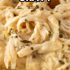 Close-up of crockpot chicken and gravy, garnished with herbs.