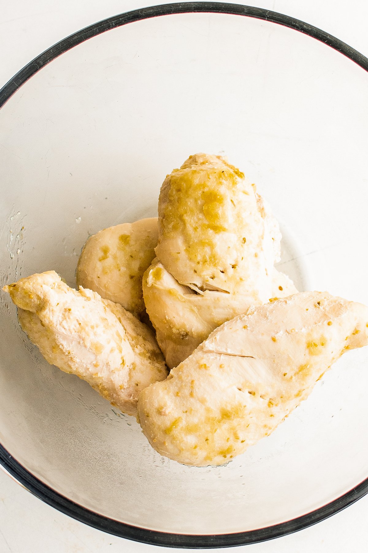 Crockpot Salsa Verde Chicken Tacos are an easy Taco Tuesday recipe! Made with tangy, savory salsa verde, they're bold, flavorful, and fun. Cooked chicken breast in a glass bowl.