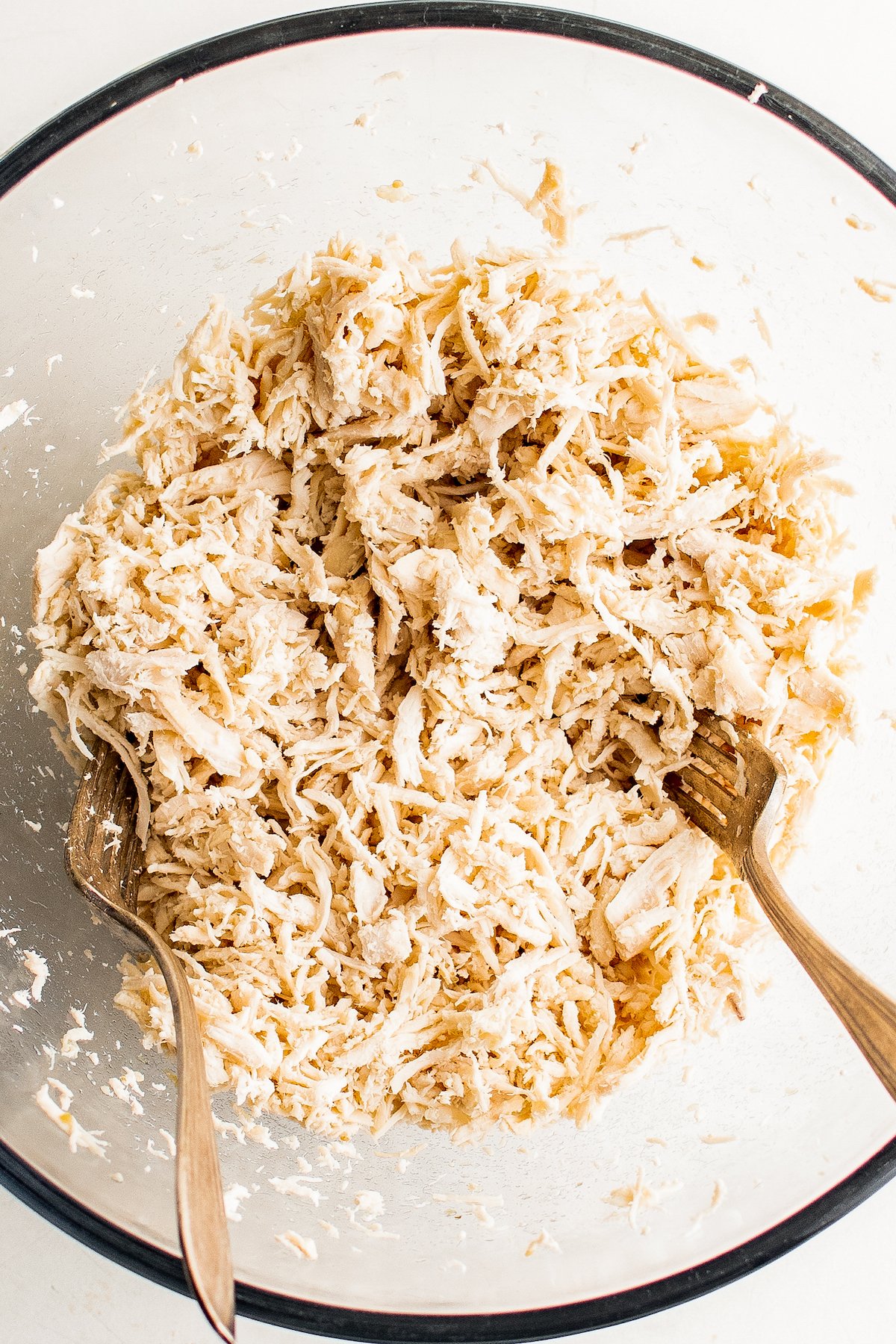 Crockpot Salsa Verde Chicken Tacos are an easy Taco Tuesday recipe! Made with tangy, savory salsa verde, they're bold, flavorful, and fun. Shredded chicken in a glass bowl.