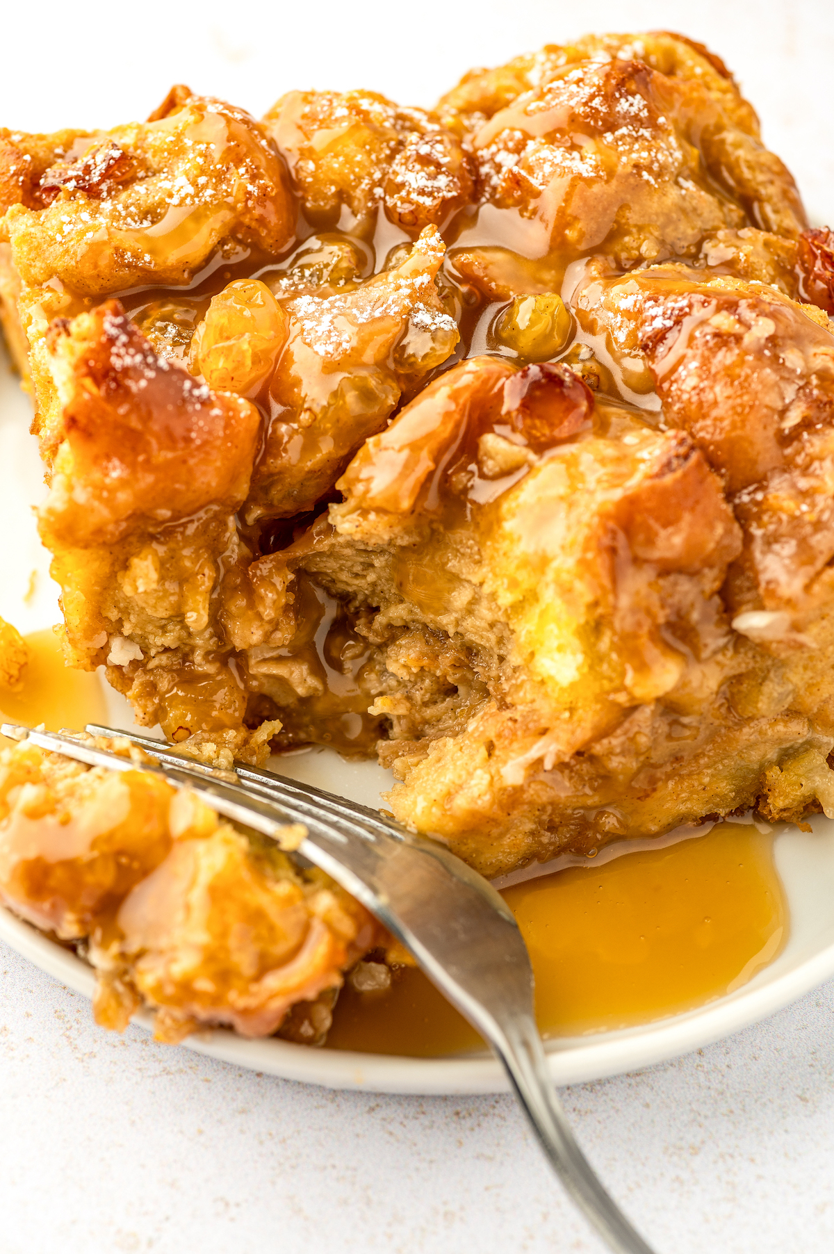 This warm and fluffy donut bread pudding with sweet raisins and buttery rum sauce is an impressive, but easy dessert you can prep ahead! Close-up of the donut pudding with rum sauce.
