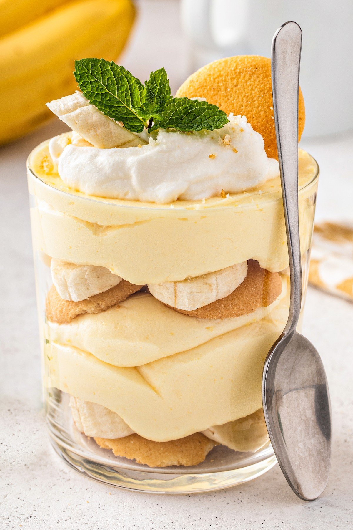 This easy banana pudding recipe has layers of fresh bananas, creamy pudding, vanilla wafers & whipped cream. The best banana pudding ever! A personal sized banana pudding with a spoon leaning against it