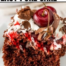 A slice of Black Forest poke cake topped with whipped cream, chocolate shavings, cherry sauce, and whole cherries on a white plate.