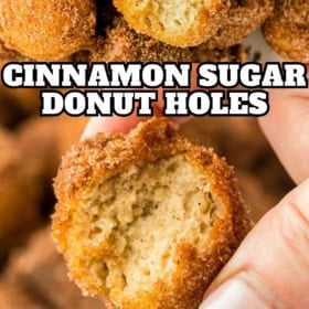A bitten into cinnamon sugar donut hole is held up by a hand.
