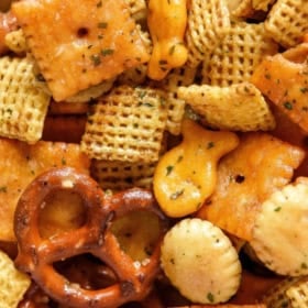 Close-up of a homemade Chex Mix with pretzels, Chex cereal, cheese crackers, oyster crackers, and goldfish.