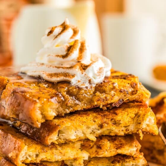 Piped whipped cream on top of a stack of fluffy pumpkin spice French toast.