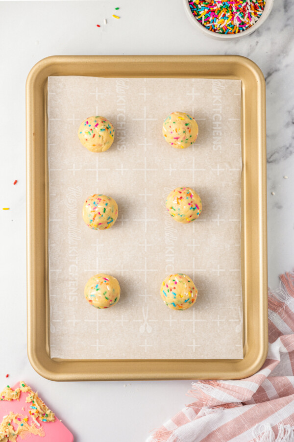 These cute, colorful Funfetti Cookies are soft, sweet, and simple to make. One cheerful sprinkle cookie just isn’t enough! Balls of cookie dough on a baking sheet.