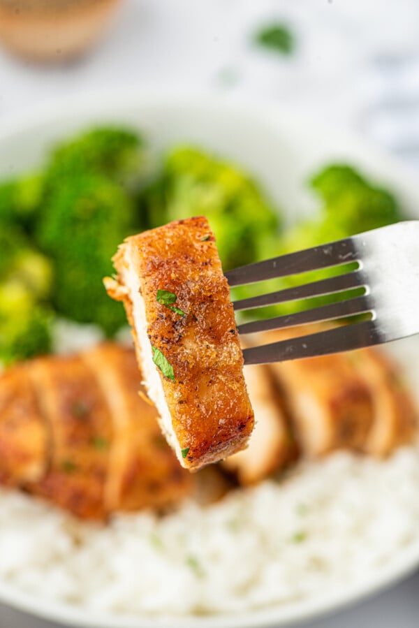 This tender and juicy garlic brown sugar chicken recipe is an easy sweet and savory dinner. You only need 4 ingredients and 25 minutes! A fork taking a bite of chicken off a plate.