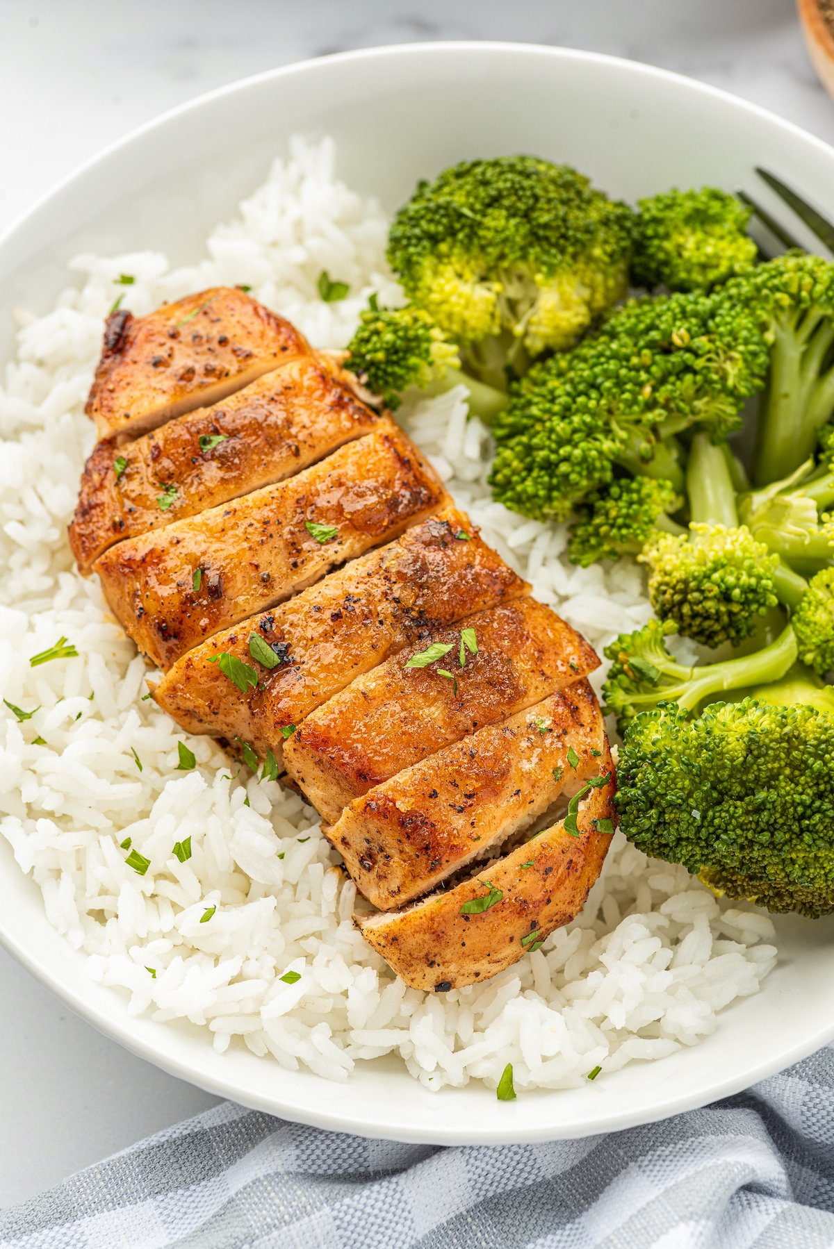 This tender and juicy garlic brown sugar chicken recipe is an easy sweet and savory dinner. You only need 4 ingredients and 25 minutes! Sliced chicken over white rice with a side of steamed broccoli.