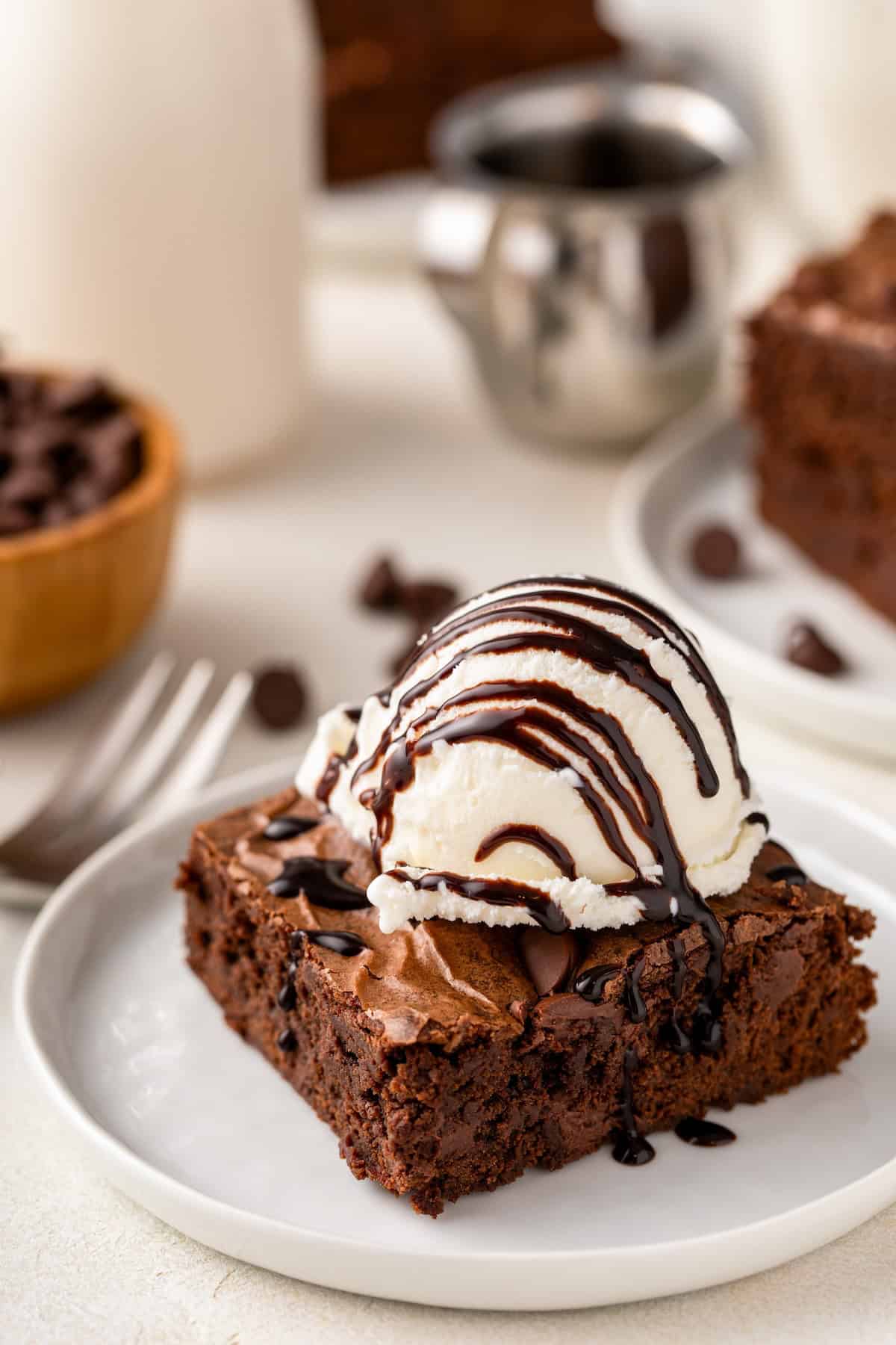 Made easy in just one-bowl, this fudge-y Homemade Brownie recipe delivers the perfect rich and chewy brownie with a crackly top! A scoop of vanilla ice cream on top of a homemade brownie is topped with a drizzle of chocolate sauce.
