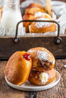 Three homemade filled donuts on a plate. Each with a different filling.